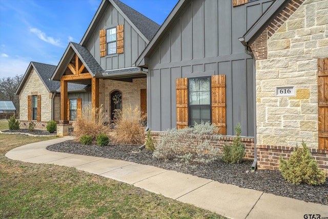 view of front of house with brick siding, stone siding, board and batten siding, and a shingled roof