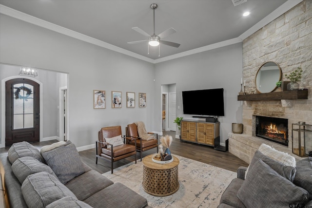 living room with crown molding, ceiling fan, baseboards, a fireplace, and wood finished floors