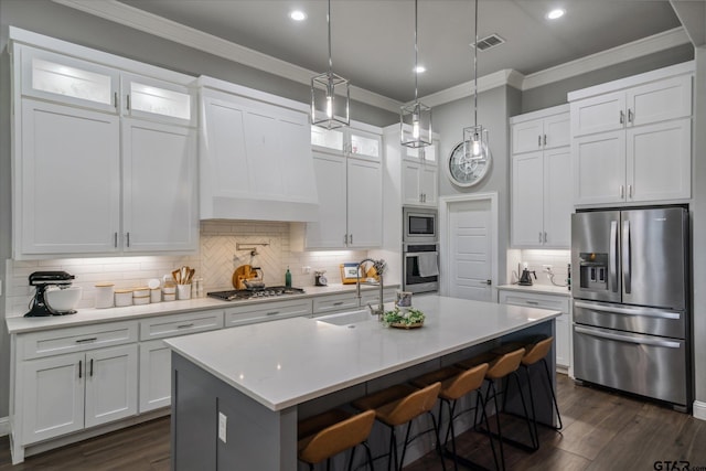 kitchen featuring visible vents, light countertops, ornamental molding, stainless steel appliances, and a sink