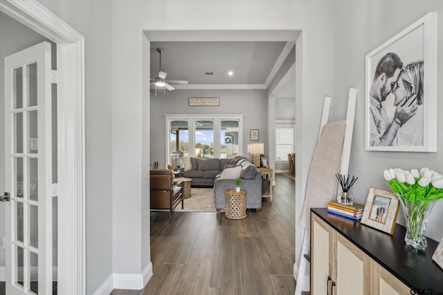 interior space with dark wood finished floors, a ceiling fan, baseboards, and ornamental molding