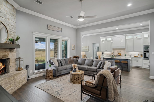 living room featuring visible vents, ornamental molding, a fireplace, and dark wood-style flooring