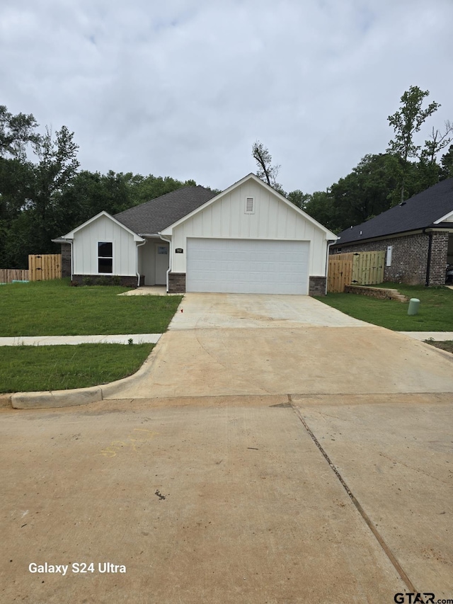 ranch-style home with board and batten siding, driveway, a front yard, fence, and an attached garage