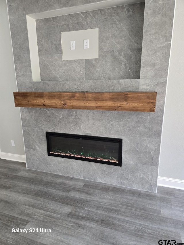 room details featuring baseboards, wood finished floors, and a fireplace