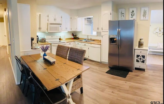 kitchen featuring white cabinetry, light hardwood / wood-style floors, sink, and white appliances