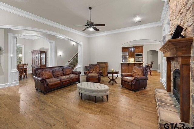 2322 Kingsmill Cir, Tyler, TX 75703 - living area featuring arched walkways, ceiling fan, light wood-style floors, stairs, and a fireplace
