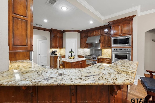 2322 Kingsmill Cir, Tyler, TX 75703 - kitchen featuring appliances with stainless steel finishes, arched walkways, under cabinet range hood, ornamental molding, and decorative backsplash