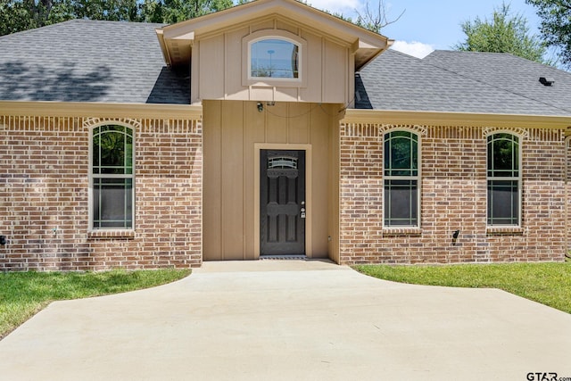 1720 Outer Dr, Tyler, TX 75701 - doorway to property with brick siding, a shingled roof, and board and batten siding