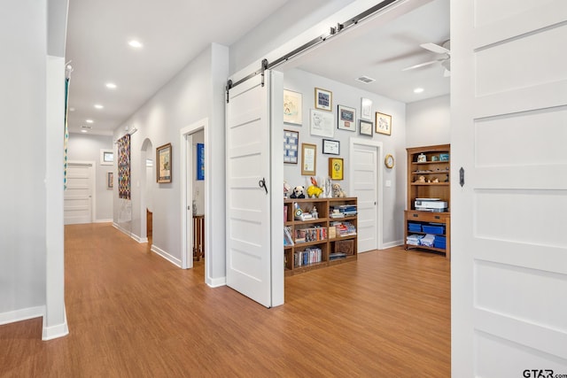 hall with a barn door and light hardwood / wood-style floors