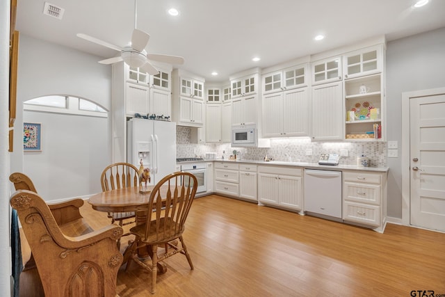 kitchen with white cabinetry, ceiling fan, backsplash, white appliances, and light hardwood / wood-style flooring