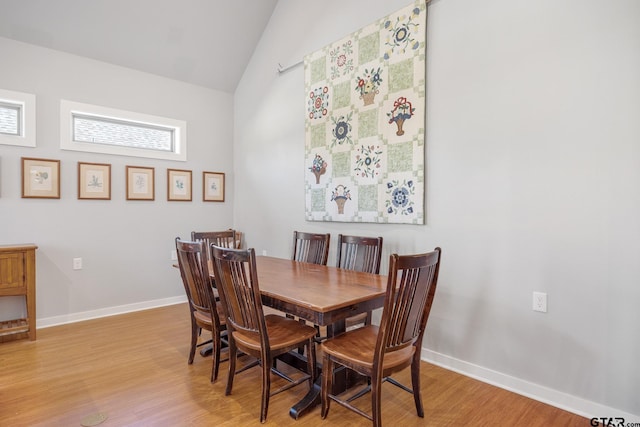 dining space with light wood-type flooring and lofted ceiling