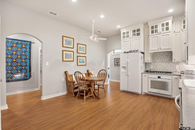 kitchen with tasteful backsplash, white cabinetry, white appliances, ceiling fan, and light hardwood / wood-style flooring