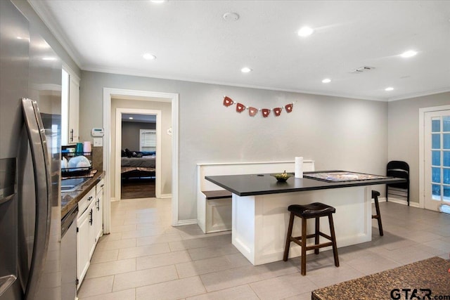 1216 Kingspark Dr, Tyler, TX 75703 - kitchen with a breakfast bar, crown molding, white cabinets, dark countertops, and appliances with stainless steel finishes