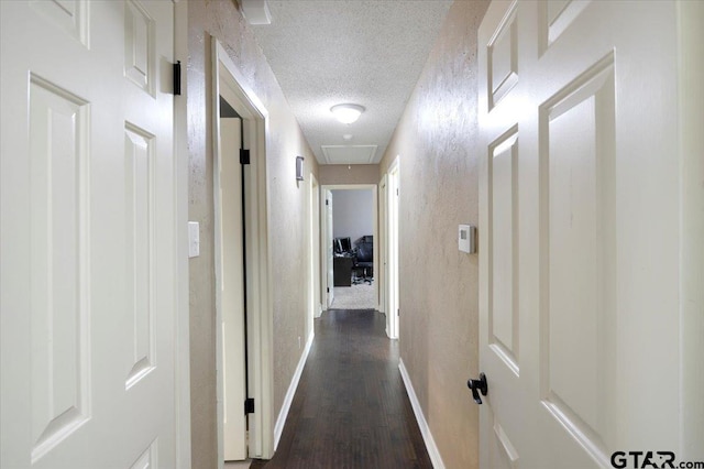 1216 Kingspark Dr, Tyler, TX 75703 - hallway with attic access, a textured ceiling, dark wood-style flooring, and baseboards