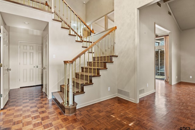 stairway with a towering ceiling and parquet floors