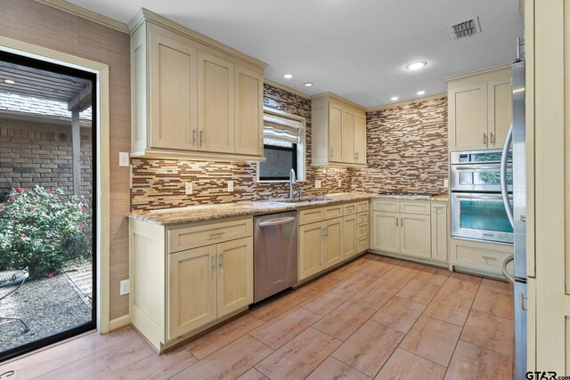 kitchen with light hardwood / wood-style floors, cream cabinets, stainless steel appliances, and sink