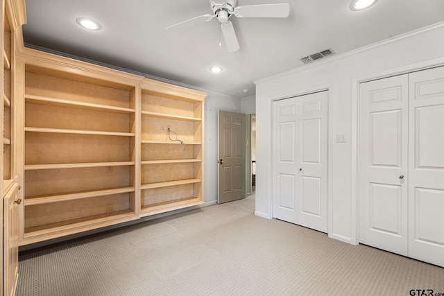 unfurnished bedroom with ceiling fan, crown molding, light colored carpet, and two closets