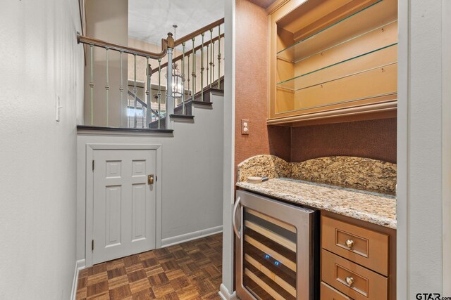 interior space featuring dark parquet flooring, light stone countertops, and beverage cooler