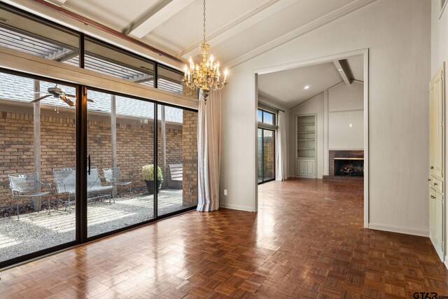 interior space with ceiling fan with notable chandelier, dark parquet flooring, lofted ceiling with beams, and a brick fireplace