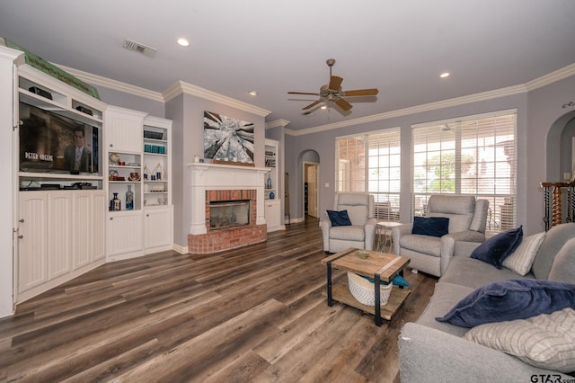 living room featuring dark hardwood / wood-style floors, ceiling fan, a fireplace, and crown molding