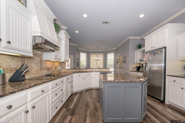 kitchen with white cabinetry, a center island, stainless steel fridge, and black electric cooktop