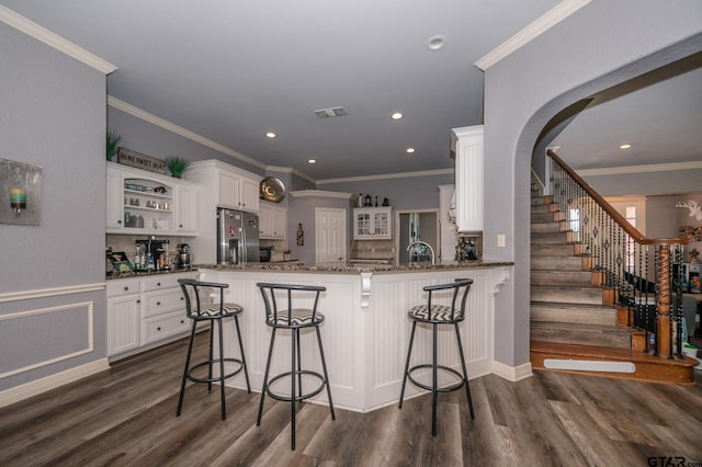 kitchen with stainless steel refrigerator with ice dispenser, white cabinetry, a kitchen breakfast bar, and kitchen peninsula