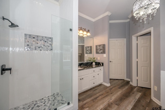 bathroom with ornamental molding, tiled shower, hardwood / wood-style floors, and vanity