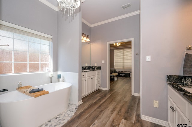 bathroom with ornamental molding, vanity, wood-type flooring, and a tub