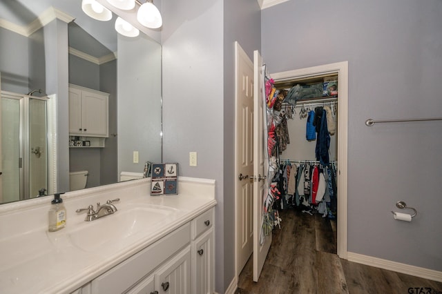 bathroom featuring hardwood / wood-style flooring, crown molding, vanity, a shower with shower door, and toilet