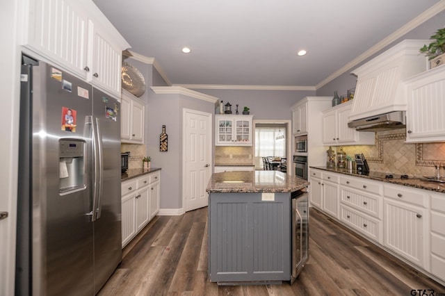 kitchen featuring a kitchen island, appliances with stainless steel finishes, ventilation hood, white cabinetry, and dark stone counters