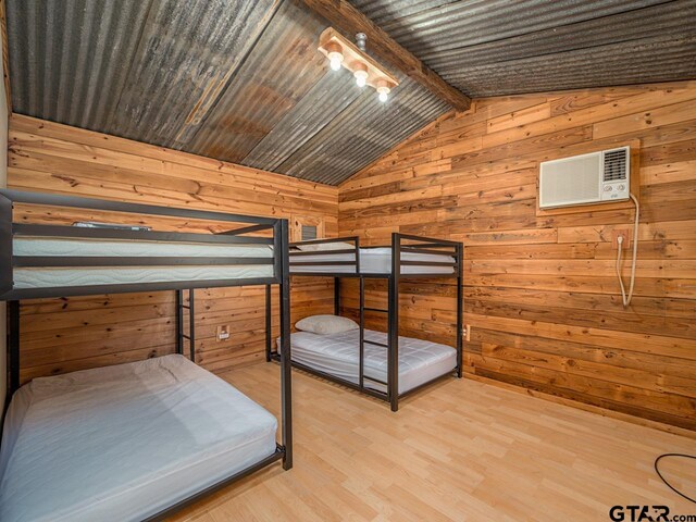 22090 Sportsmans Dr, Chandler, TX 75758 - bedroom with wood walls, a wall unit AC, and light wood-style floors