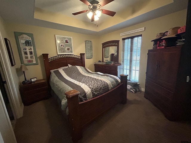 carpeted bedroom with ceiling fan and a raised ceiling