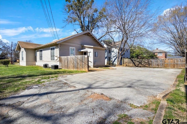 view of home's exterior with aphalt driveway, a lawn, and fence