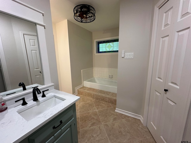 bathroom with tile patterned floors, vanity, and a relaxing tiled tub