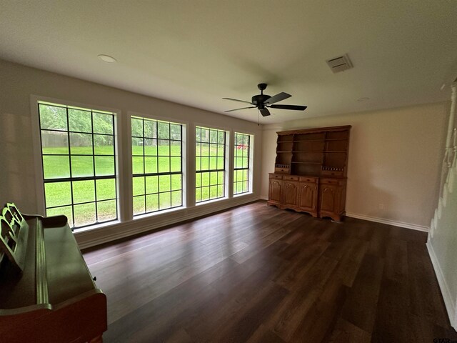 unfurnished living room with dark wood-type flooring, a wealth of natural light, and ceiling fan