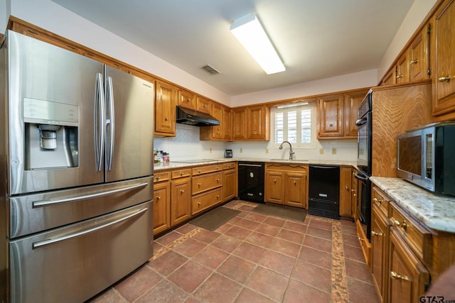 kitchen with brown cabinets, visible vents, under cabinet range hood, and black appliances