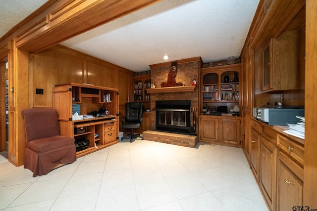 living area featuring light tile patterned floors, built in desk, wood walls, and a fireplace