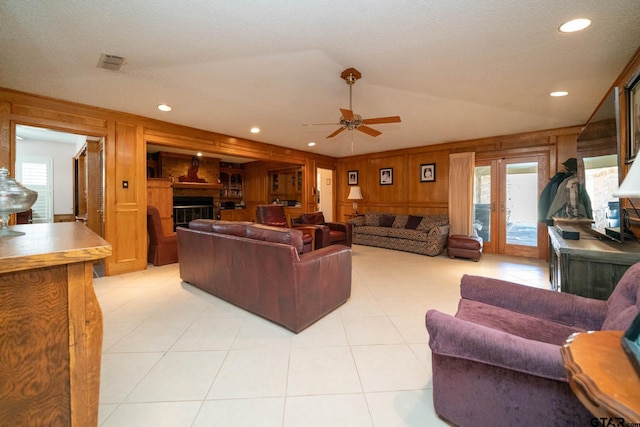 living area featuring light tile patterned floors, visible vents, wood walls, a fireplace, and recessed lighting