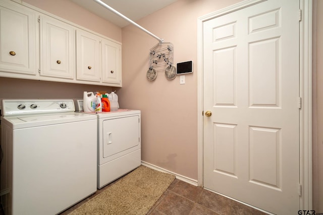 clothes washing area featuring washing machine and dryer, cabinet space, and baseboards