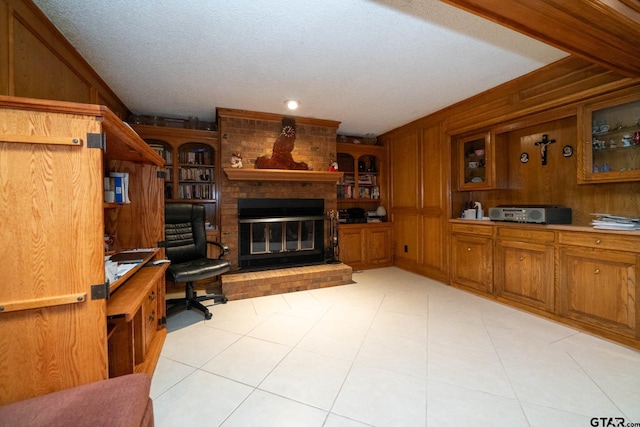 living room featuring wooden walls, a fireplace, light tile patterned floors, and a textured ceiling