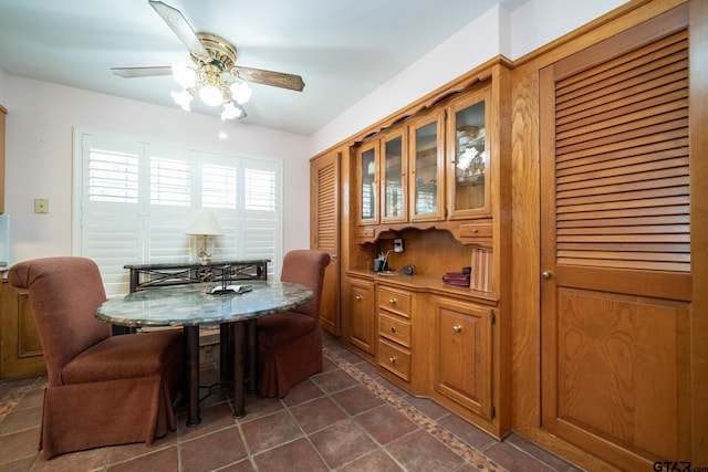 dining space with a ceiling fan and dark tile patterned floors