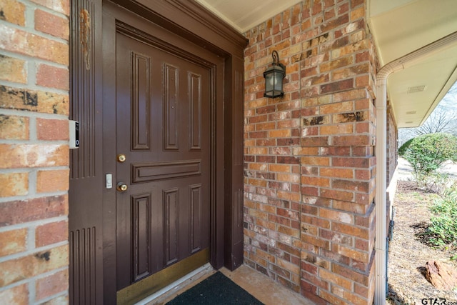 doorway to property featuring brick siding