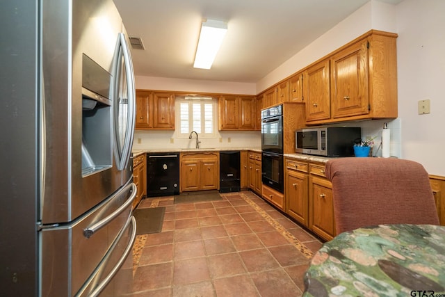 kitchen with black appliances, light countertops, visible vents, and brown cabinets