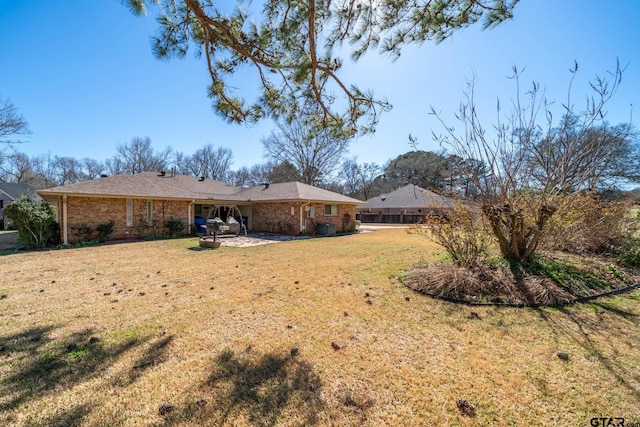 rear view of house with a patio, a lawn, and brick siding