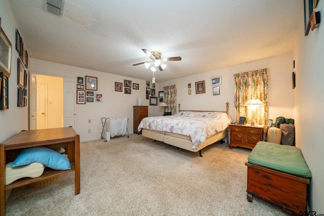 bedroom with light carpet, a textured ceiling, visible vents, and a ceiling fan