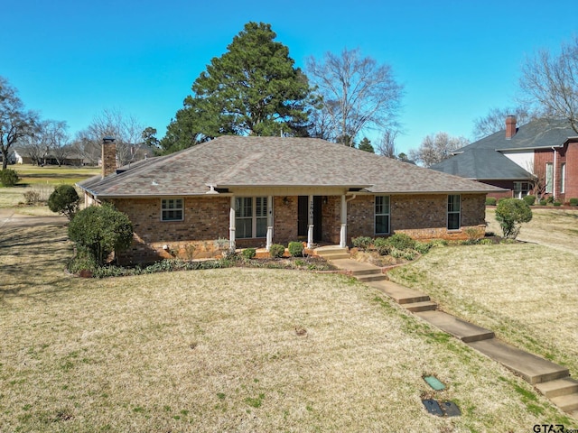 ranch-style home featuring a shingled roof, brick siding, a chimney, and a front lawn