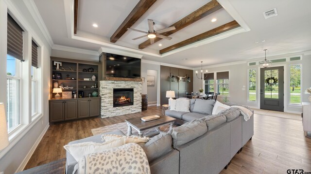 living room with visible vents, beam ceiling, wood finished floors, a fireplace, and ceiling fan with notable chandelier