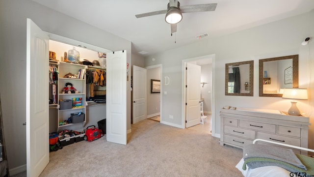 bedroom with light colored carpet, a walk in closet, baseboards, visible vents, and a closet