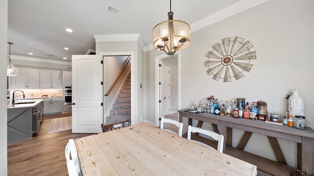 dining area with crown molding, a chandelier, recessed lighting, wood finished floors, and visible vents