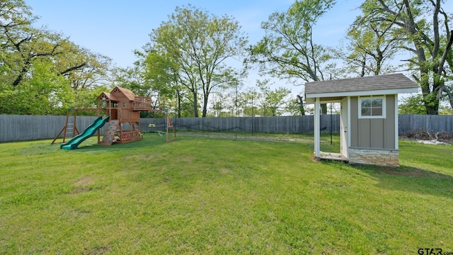 view of yard with a storage shed, an outbuilding, a fenced backyard, and a playground
