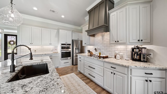 kitchen featuring decorative backsplash, visible vents, a sink, stainless steel appliances, and wall chimney exhaust hood